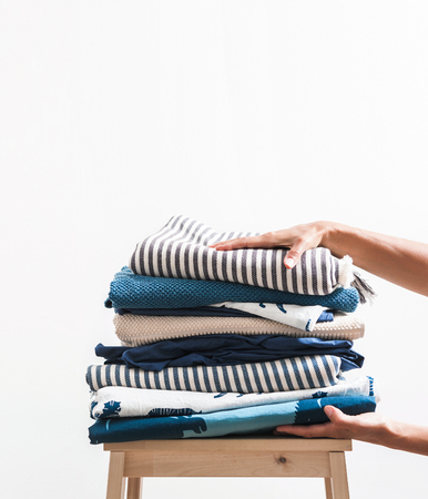 Woman hands take stack of blue and beige laundryの写真素材