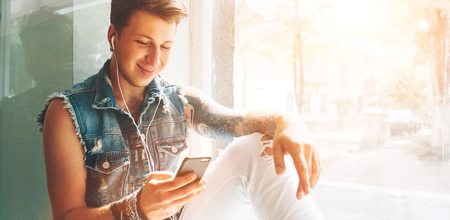 Young man listen music with headphones and smartphone sittingの写真素材