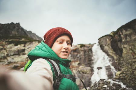 Boy mountain hiker invite somebody walk with him to waterfallの写真素材