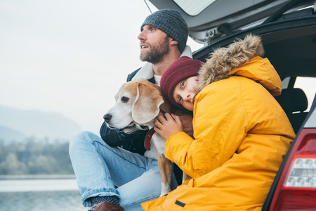 Father and son with beagle dog siting together in car trunk. Late autumn timeの写真素材