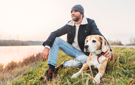 Man with beagle dog sitting together near the lakeの写真素材