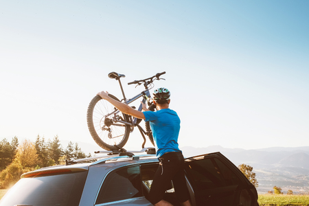 Mountain biker man take of his bike from the car roofの写真素材