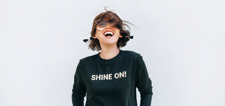 Free feeling happy woman posing in black sweatshirt with positive print Shine Onの写真素材
