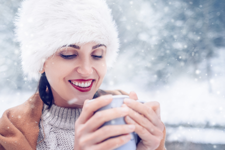 Happy smiling Woman with cup of hot tea in snow forestの写真素材