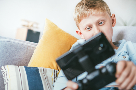 Preteen boy plays games with smartphone connected with gamepadの写真素材