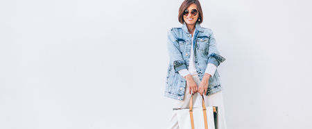 Elegant woman dressed in oversize denim jacket and wide white trousersの写真素材