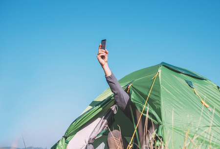 Traveler try to catch cellular network putting out hand from tourist tent.の写真素材