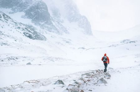 Climber walks alone in high mountains at windy snowy weatherの写真素材