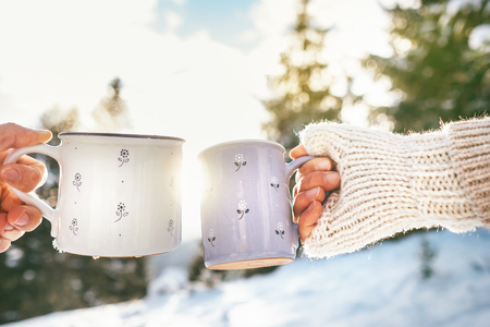 Man and woman hands in knitting mittens taking cups of hot drink.の写真素材