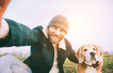 Cheerful smiling Man takes selfie photo with his best friend beagle dog during walking.の写真素材