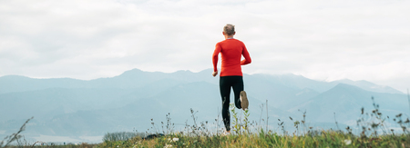 Wide angle shoot of a Man dressed in red long sleeve shirt runs by the road with mountainの写真素材