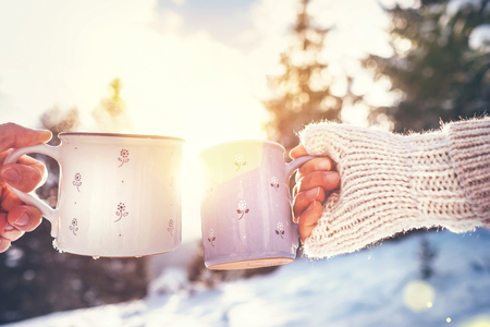 Man and woman hands in knitting mittens taking cups of hot drink.の写真素材