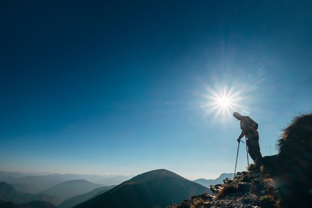 Backpacker hiker on the mountain hill in contrast sunlight going down in the high mountain.の写真素材