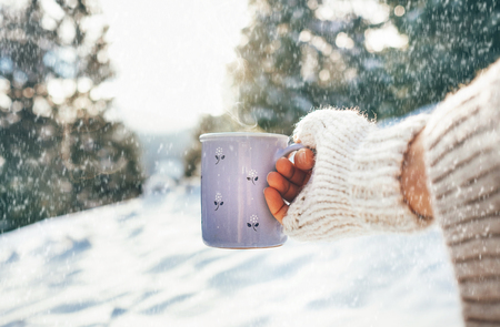 Woman take in hand cup of hot drink. Winter forest glade, bright sunny scene. Point of View POV shot.の写真素材