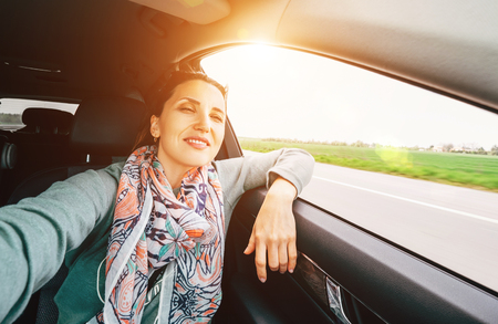 Woman with wavy hair looks out car window wide angle shot.の写真素材