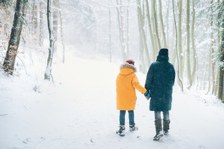 Mother and son walking in snowy forest. Mother and son relatives concept image.の写真素材