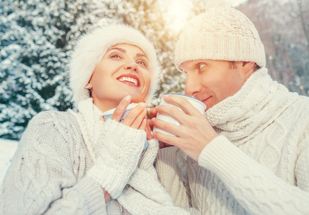 Cozy dressed couple in love drink hot of tea in winter forestの写真素材