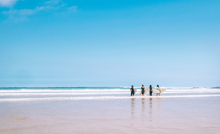 Group surfers girls with boards stay on ocean surf line and ready to go into water. Never ending summer surfing concept image.の写真素材