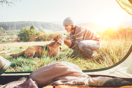 Woman and her dog tender scene near the camping tent. Active leisure, traveling with pet6 simple things concept imageの写真素材