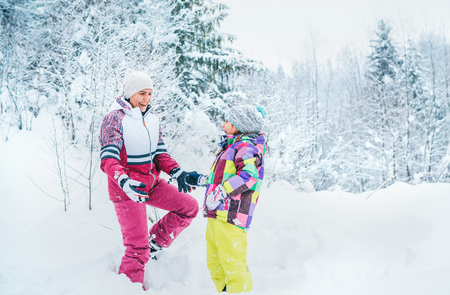 Happy smiling mother and daughter portrait in snow forest. Happy parents and kids relations concept imageの写真素材