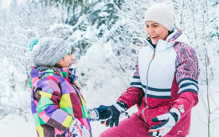 Happy smiling mother and daughter portrait in snow forest. Happy parents and kids relations concept imageの写真素材