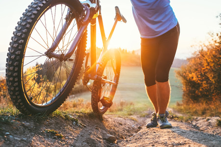 Cyclist man pushing a mountain bike up the hill close up image. Active travel on bicycleの写真素材