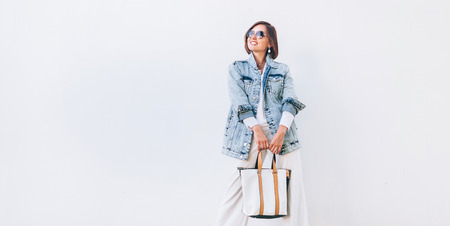 Woman in elegant outfit with oversize denim jacket and shopper bagの写真素材
