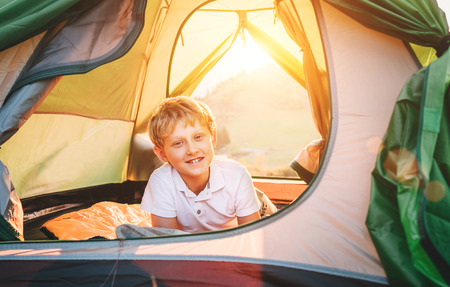Boy rest in camping tent. Sunset time in natureの写真素材