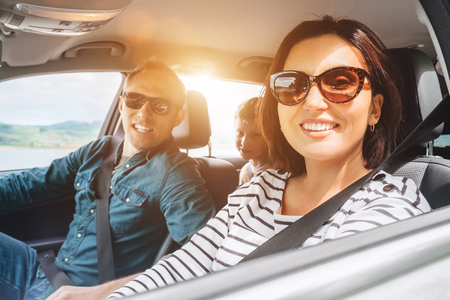 Cheerful young traditional family has a long auto journey and smiling together. Safety riding car concept inside car wide angle view image.の写真素材