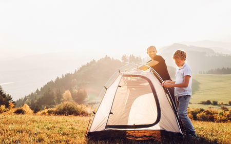 Father and son installing tent on forest glade.Trekking with kids concept imageの写真素材