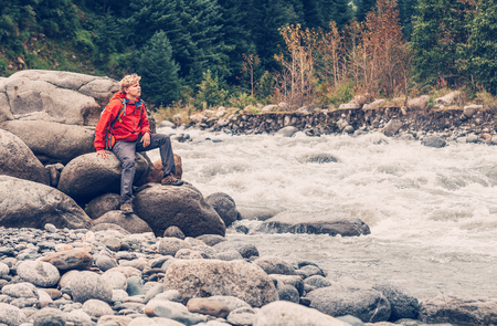 Man traveler sits on mountain river bankの写真素材