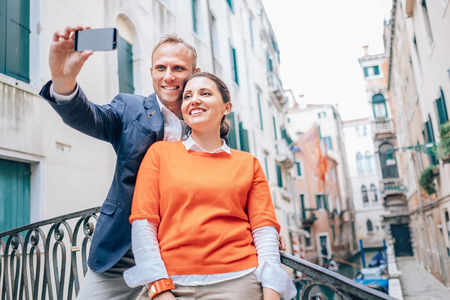 Happy in love couple take selfie photo on one of numerous bridge in Venice, Italyの写真素材