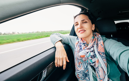 Woman in car portrait with wavy hair looks out car window wide angle shot.の写真素材