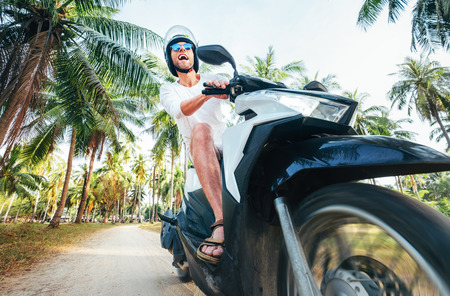 Man riding motorbike under palm treesの写真素材