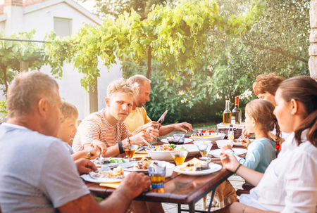 Big multigeneration family have dinner on open garden terraceの写真素材