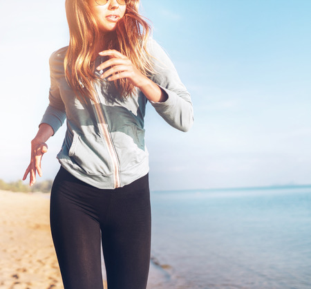 Fashionable young longhaired woman have morning jogging on the calm sea coastの写真素材