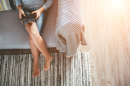 Boy sits on sofa plays with smartphone and gamepad camera top view. Child and electronic devices conceptの写真素材