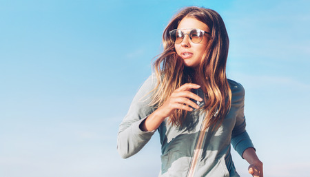 Fashionable young longhaired woman have morning jogging on the calm sea coastの写真素材