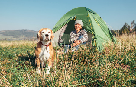 Woman with her pet beagle dog rest in camping tentの写真素材