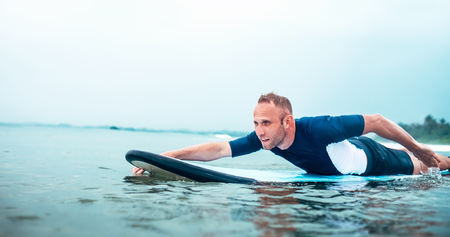 Man padding to line up on the surf board.  Active holidays spending concept.の写真素材