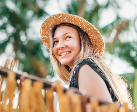 Positive young woman smiling sitting in hammock on the tropical palm beachの写真素材