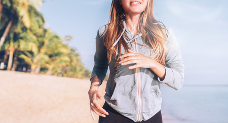 Smiling young longhaired woman have morning jogging on the seaside beachの写真素材