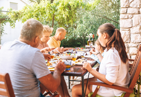 Big multigeneration family have dinner on open garden terraceの写真素材