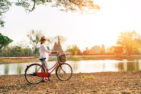 Young female traveler weared light summer clothes and hat have early morning walk with bicycleの写真素材
