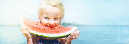 Little girl in pink sunglasses with big watermelon segment funny portrait. Healthy eating concept image.の写真素材