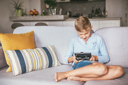 Teenager boy emotionaly plays on the game console connected with smartphoneの写真素材