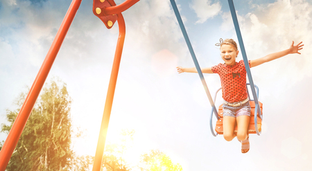 Little laughing girl swing on swing. Happy childchood concept image.の写真素材