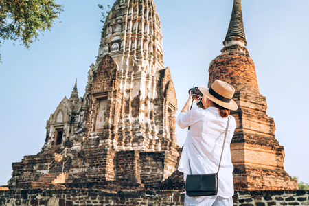 Woman traveler takes a phoot of atcient Wat Chaiwatthanaram Buddhist temple in the city of Ayutthaya Historical Park, Thailandの写真素材