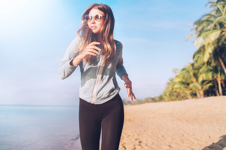 Fashionable young longhaired female have morning jogging on the seaside beachの写真素材