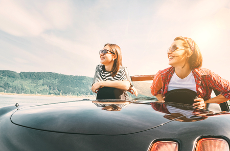 Two females friends traveling by cabriolet, have a stop brake to enjoy a mountain landsxapesの写真素材